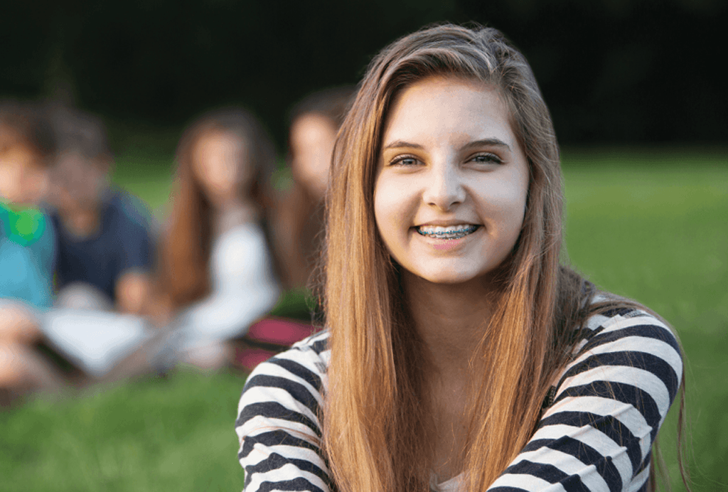 Teenage girl with metal braces sitting outside